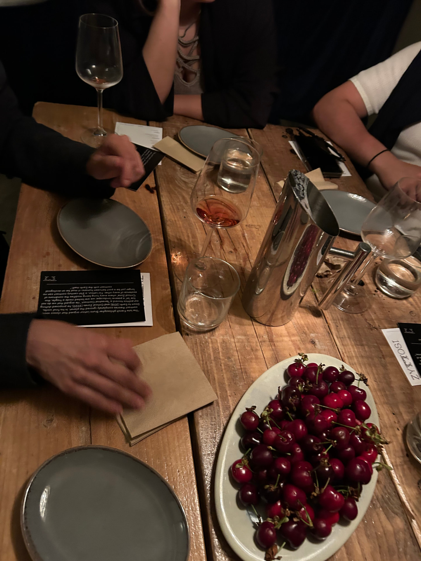 A candlelit dinner table with a plate of cherries and glasses of wine
