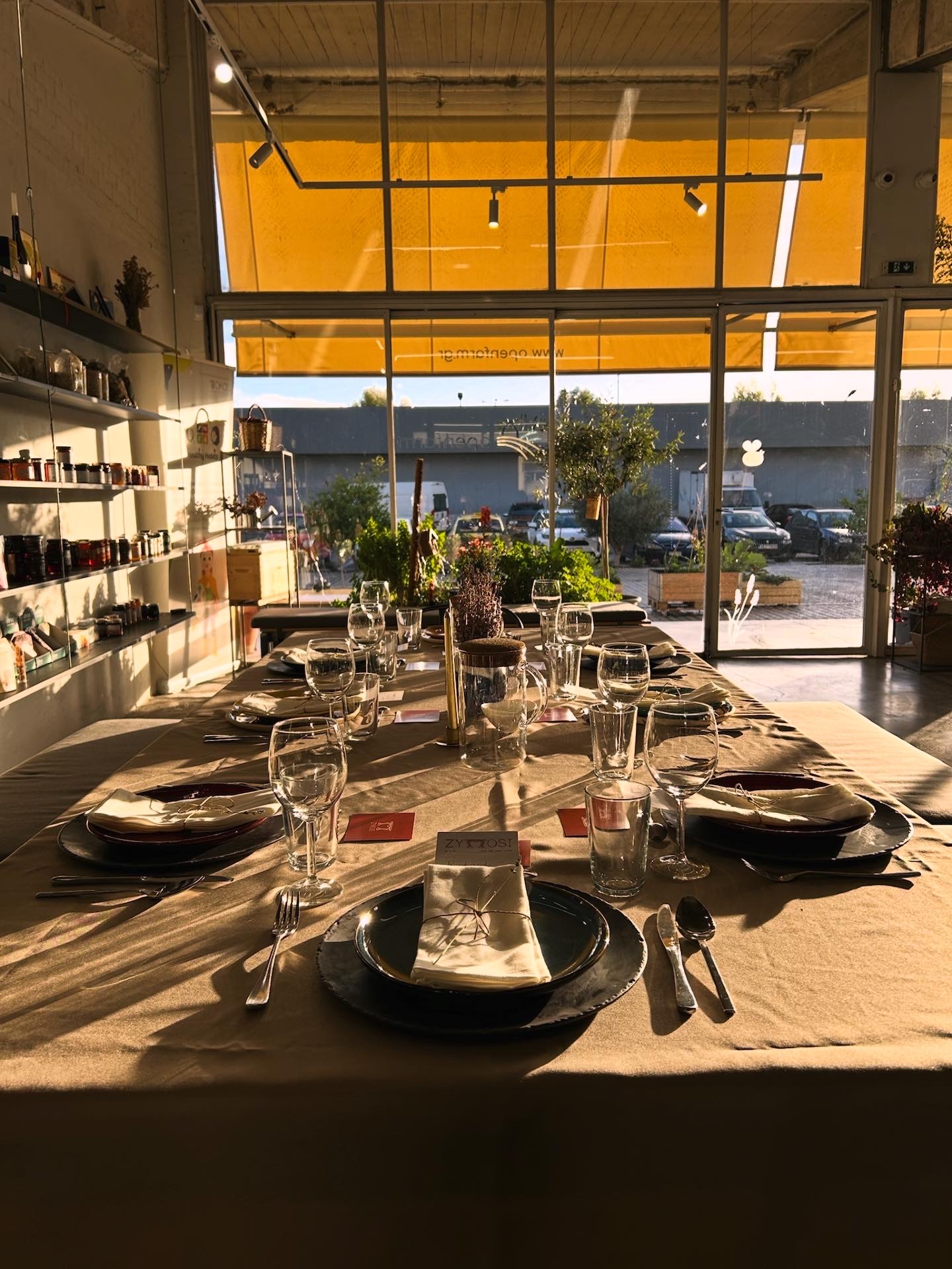 A long Zymosi table set with plates, glasses and place cards in golden afternoon light